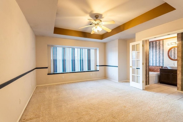 carpeted spare room featuring ceiling fan and a tray ceiling