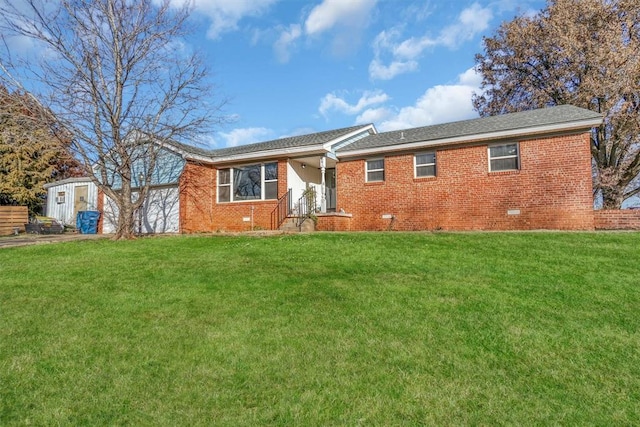 rear view of property with a yard and a storage unit