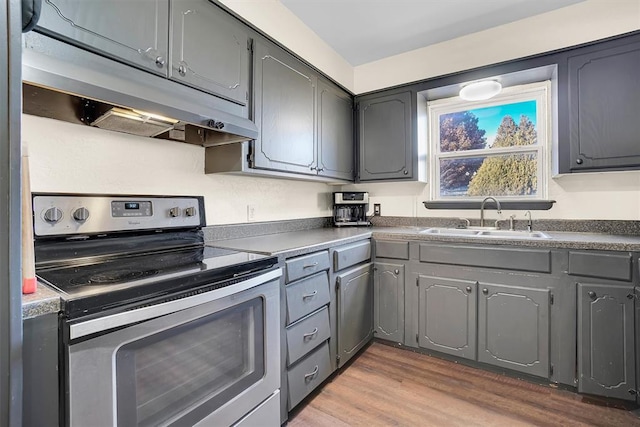 kitchen featuring hardwood / wood-style floors, stainless steel electric stove, gray cabinetry, and sink