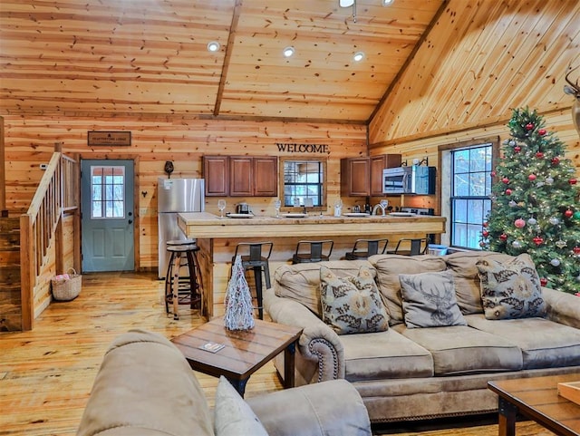 living room with high vaulted ceiling, wooden ceiling, light hardwood / wood-style flooring, and a healthy amount of sunlight