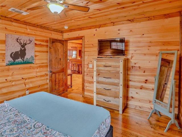 bedroom with light wood-type flooring, ceiling fan, wooden ceiling, and wood walls