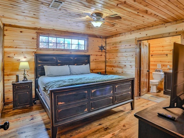 bedroom with ceiling fan, wooden ceiling, wood walls, ensuite bathroom, and hardwood / wood-style flooring