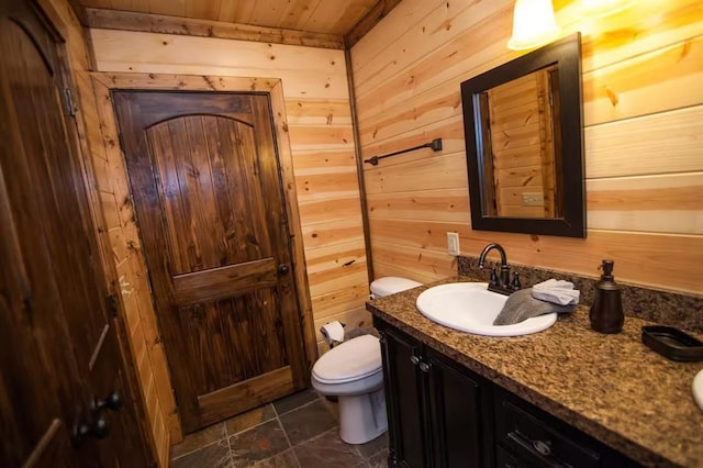 bathroom featuring vanity, toilet, wooden walls, and wood ceiling