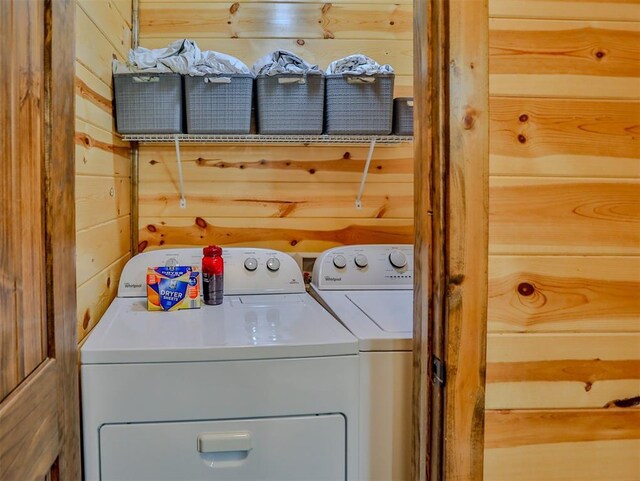 clothes washing area featuring wooden walls and washer and dryer