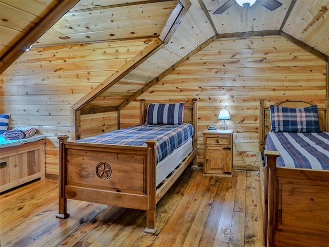 bedroom with light wood-type flooring, vaulted ceiling, ceiling fan, wooden ceiling, and wood walls