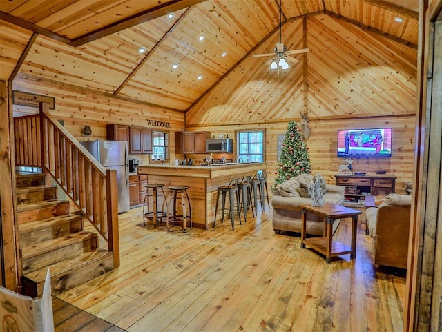 527 High Peak Trl, Broken Bow, OK 74728 - living room with high vaulted ceiling, wood walls, light wood-type flooring, ceiling fan, and stairs