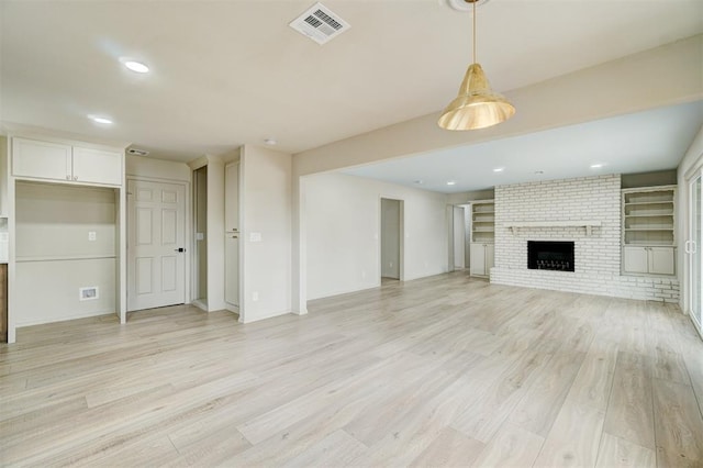 unfurnished living room with light hardwood / wood-style floors and a brick fireplace