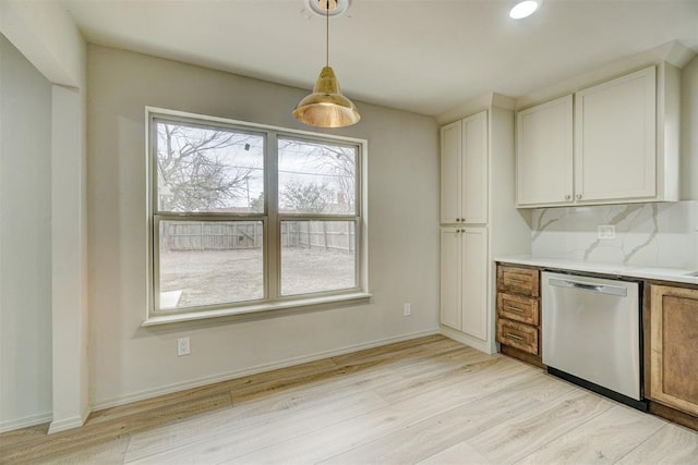 kitchen featuring backsplash, hanging light fixtures, stainless steel dishwasher, light stone countertops, and white cabinetry