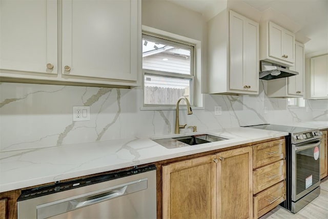 kitchen with white cabinetry, sink, light stone countertops, stainless steel appliances, and backsplash