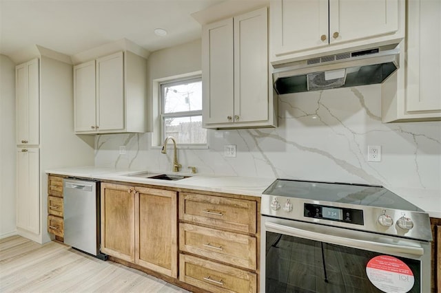 kitchen featuring sink, tasteful backsplash, light stone counters, light brown cabinetry, and appliances with stainless steel finishes