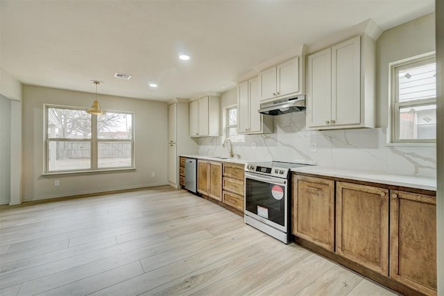 kitchen featuring white cabinetry, hanging light fixtures, light hardwood / wood-style flooring, backsplash, and appliances with stainless steel finishes