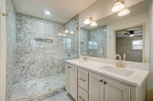 bathroom with tiled shower, vanity, and ceiling fan