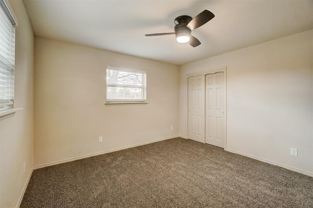 unfurnished bedroom with ceiling fan, a closet, and dark colored carpet