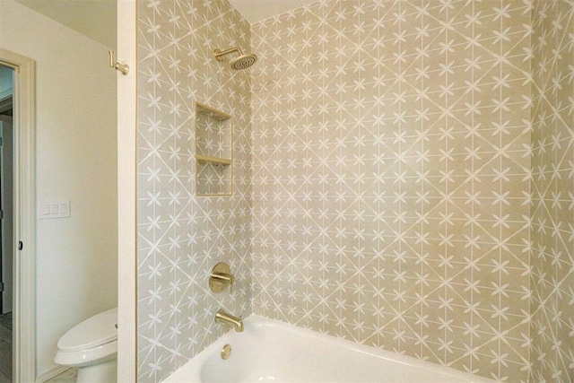 bathroom featuring tiled shower / bath combo and toilet