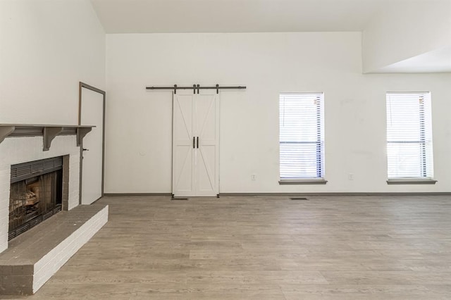 unfurnished living room featuring a barn door, a wealth of natural light, and light hardwood / wood-style floors