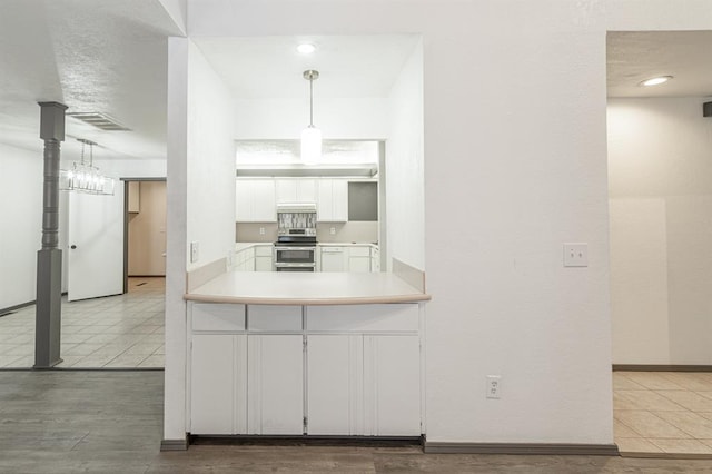 kitchen with white cabinetry, hanging light fixtures, stainless steel electric stove, and tile patterned floors