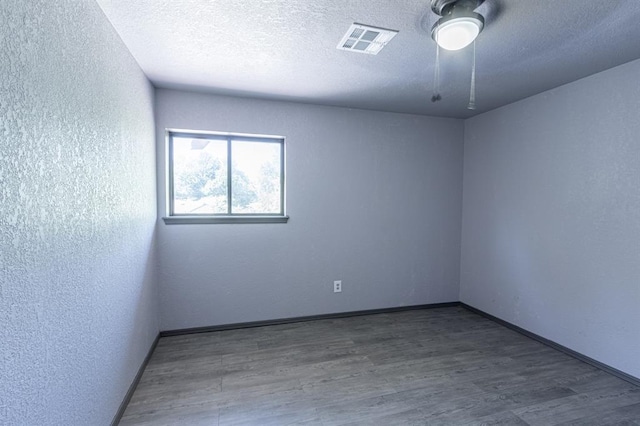 empty room with wood-type flooring and a textured ceiling