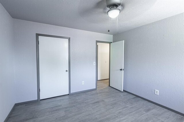 unfurnished bedroom with ceiling fan, a textured ceiling, and light wood-type flooring