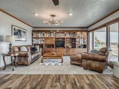 living room featuring ceiling fan with notable chandelier, a textured ceiling, light hardwood / wood-style floors, and ornamental molding