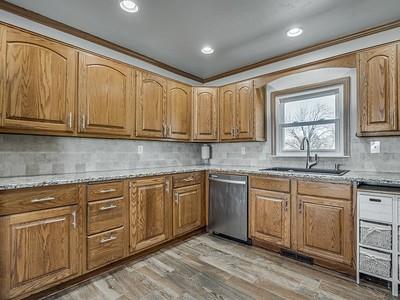 kitchen with light stone countertops, stainless steel dishwasher, crown molding, sink, and light hardwood / wood-style floors