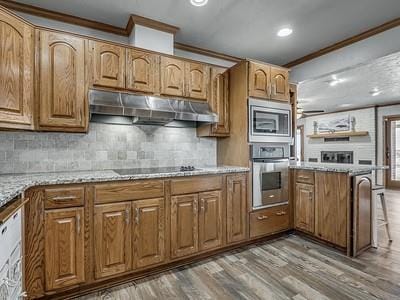 kitchen with light stone countertops, crown molding, stainless steel appliances, and wood-type flooring