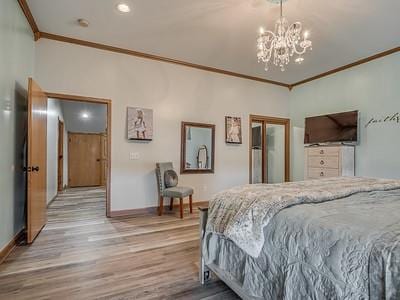 bedroom featuring light hardwood / wood-style floors, ornamental molding, and a notable chandelier