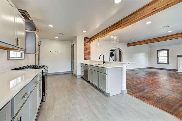 kitchen with gray cabinetry, sink, appliances with stainless steel finishes, beamed ceiling, and light hardwood / wood-style floors