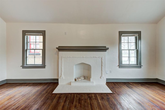 unfurnished living room featuring dark wood-type flooring and a brick fireplace