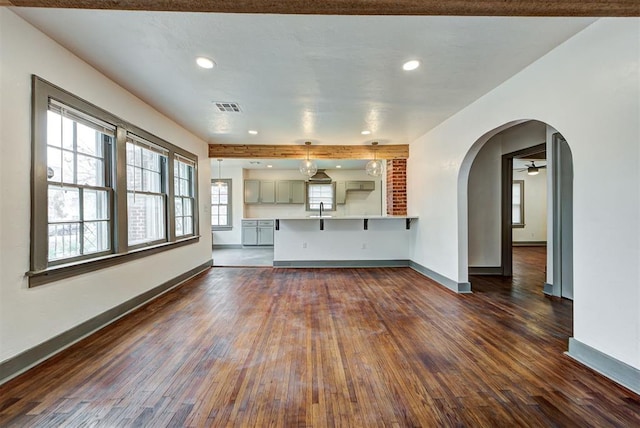 unfurnished living room featuring ceiling fan, dark wood-type flooring, and sink