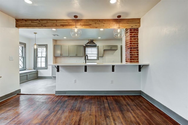 kitchen with a breakfast bar, pendant lighting, dark wood-type flooring, and gray cabinetry