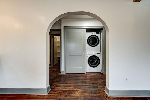 laundry area with dark hardwood / wood-style flooring and stacked washer and clothes dryer