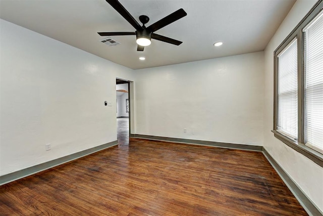 empty room with dark wood-type flooring, ceiling fan, and a healthy amount of sunlight