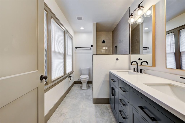 bathroom with tile patterned flooring, vanity, toilet, and a tile shower