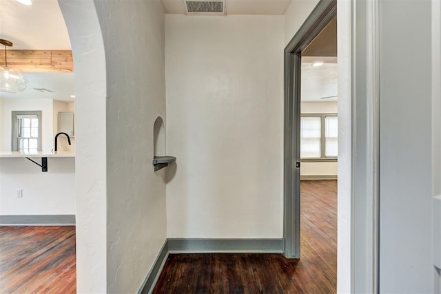 corridor with dark hardwood / wood-style flooring and sink