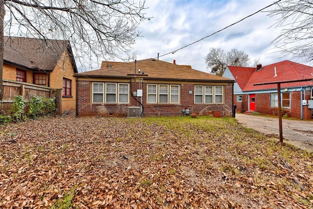 view of front of house featuring brick siding, fence, and central AC