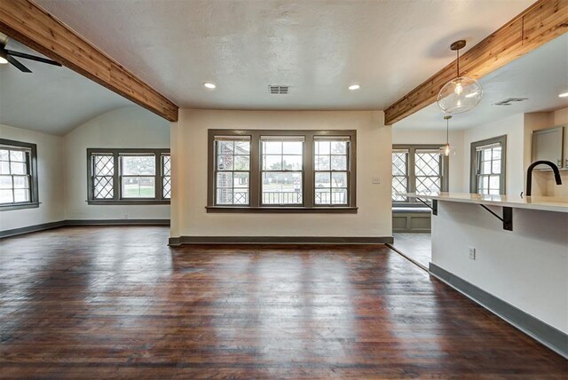 unfurnished living room featuring dark wood-style floors, visible vents, baseboards, and beam ceiling