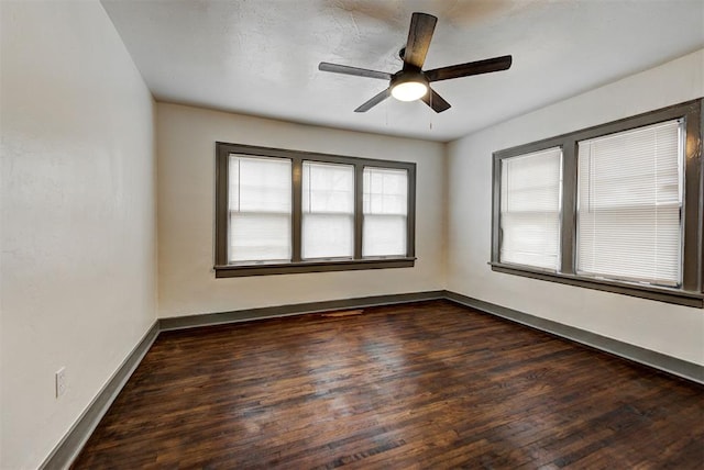 unfurnished room featuring a ceiling fan, dark wood-style flooring, and baseboards