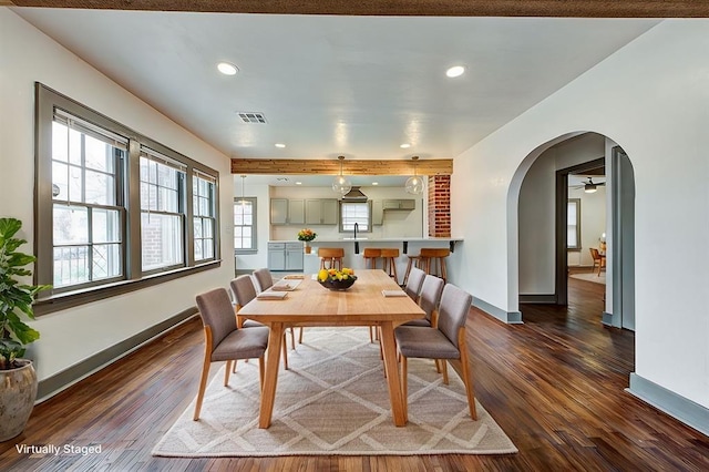 dining room with arched walkways, visible vents, dark wood finished floors, and baseboards