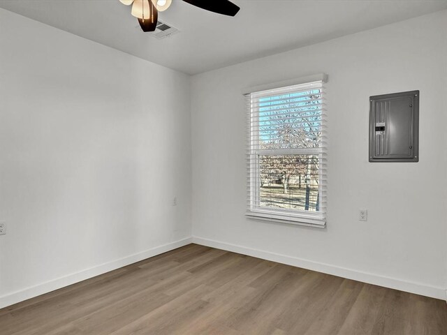 spare room with electric panel, ceiling fan, and hardwood / wood-style flooring