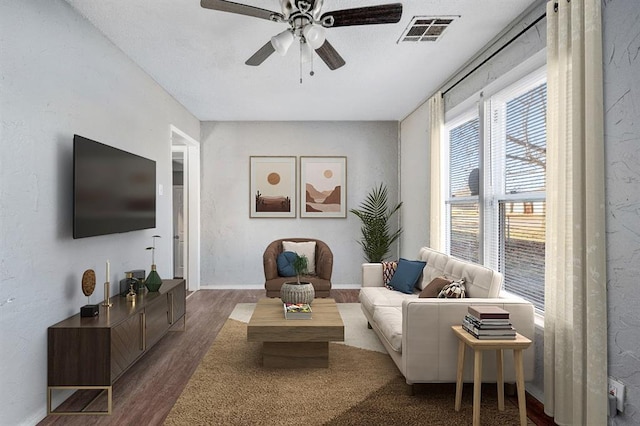 living room featuring ceiling fan and dark wood-type flooring