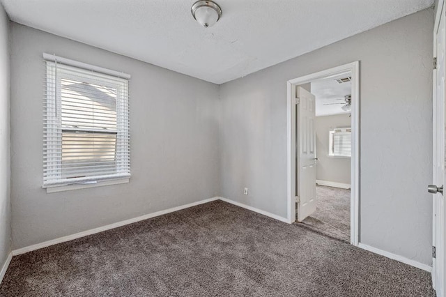 carpeted spare room featuring plenty of natural light and ceiling fan