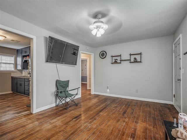 interior space featuring dark wood-type flooring, a textured ceiling, and ceiling fan