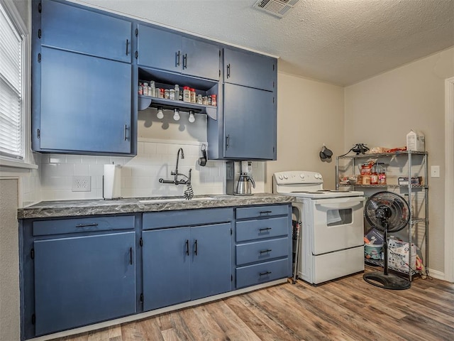 kitchen with white range with electric stovetop, blue cabinets, sink, decorative backsplash, and light wood-type flooring