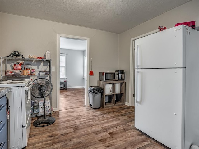 laundry room with wood-type flooring, washer / dryer, and a textured ceiling