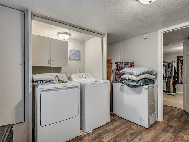 laundry room featuring cabinets, dark wood-type flooring, a textured ceiling, and washer and clothes dryer