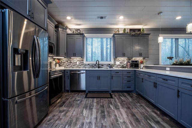 kitchen with sink, stainless steel appliances, dark hardwood / wood-style flooring, backsplash, and decorative light fixtures