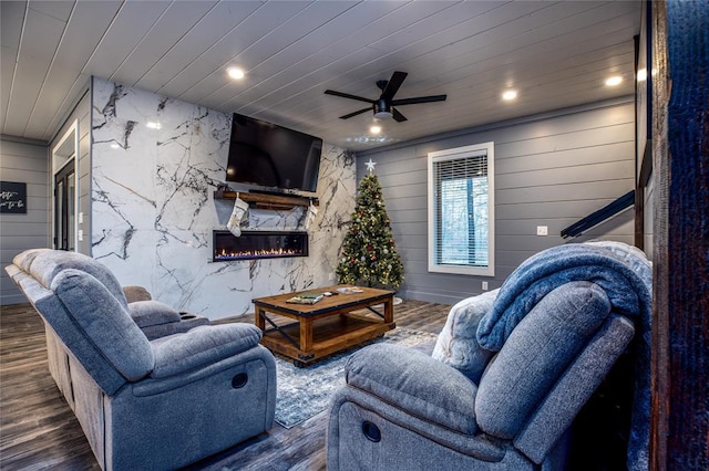 living room featuring dark hardwood / wood-style flooring, wooden ceiling, ceiling fan, and wooden walls