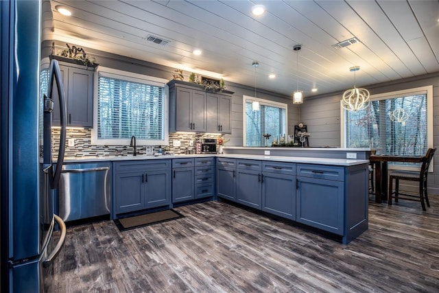 kitchen featuring kitchen peninsula, appliances with stainless steel finishes, plenty of natural light, and hanging light fixtures