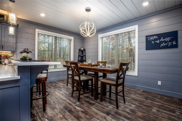 dining room featuring wooden walls, dark hardwood / wood-style flooring, and a chandelier
