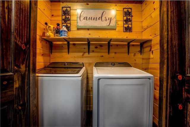 laundry area with washing machine and dryer and wooden walls
